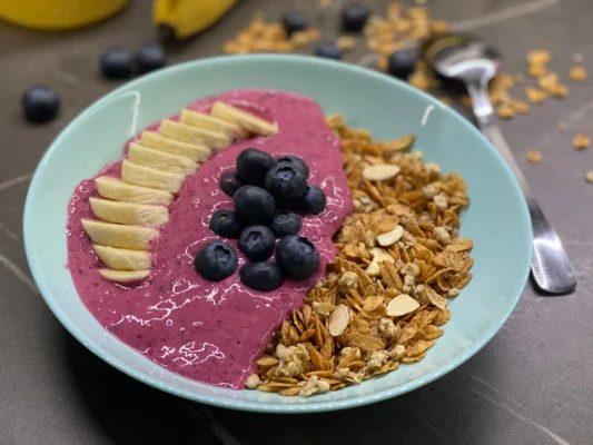 Miska plná granoly so smoothie z lesného ovocia a limetky